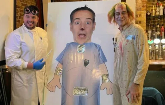 Mark Watson and co-worker standing next to What's in Watson; an operation-style game.