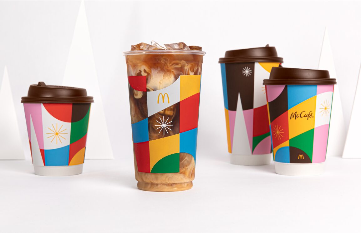 An iced coffee in the center with three coffee cups surrounding
