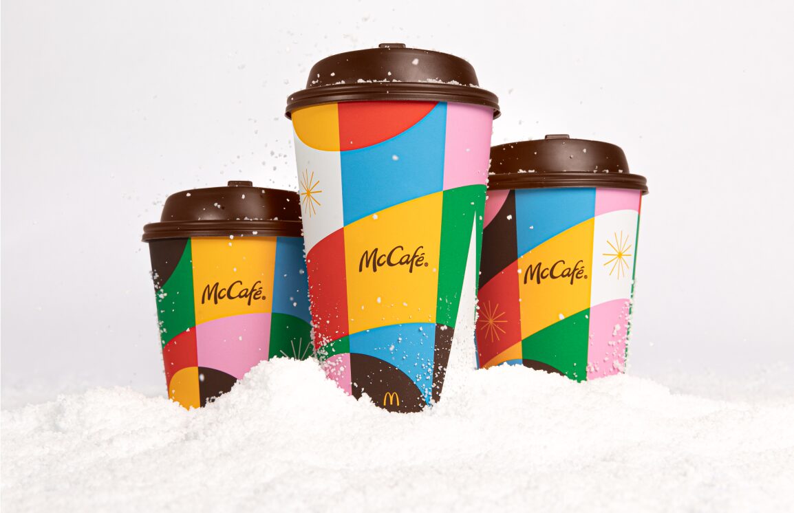 3 McCafe holiday cups with snow on the ground and a white background