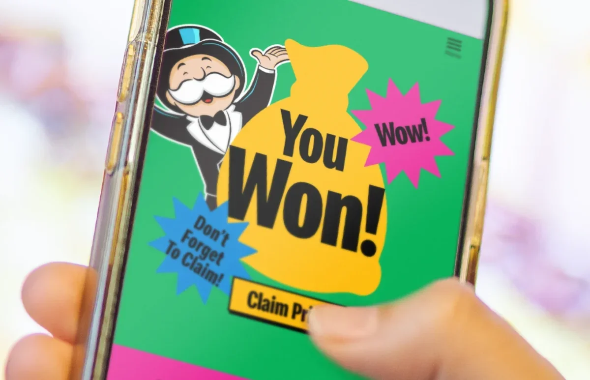 A person holding a mobile phone with the McDonalds Monopoly on the display. The words “You won!” are shown