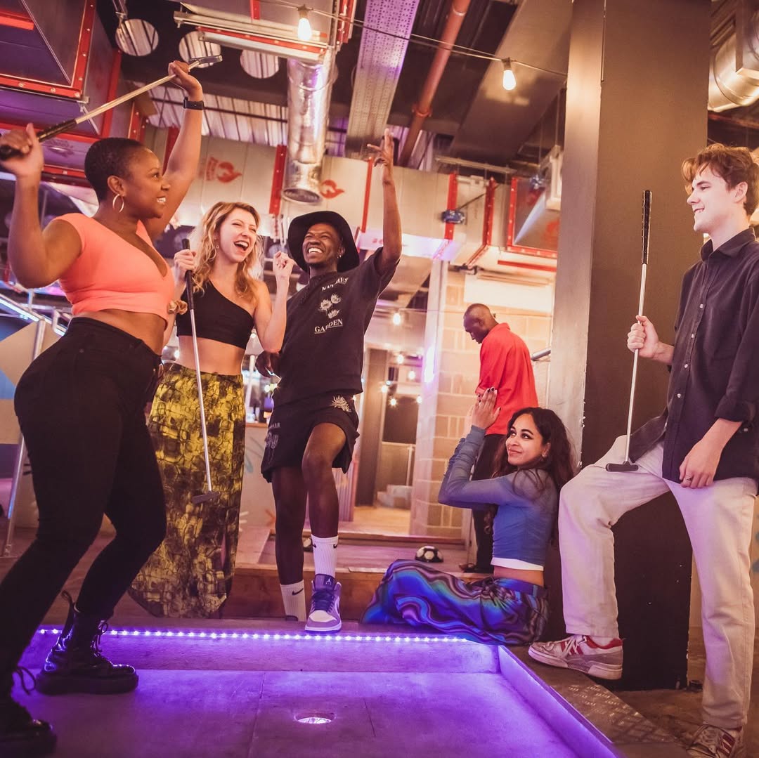 adults playing indoor minigolf