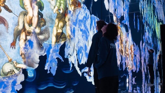 People standing in front of an illuminated mural