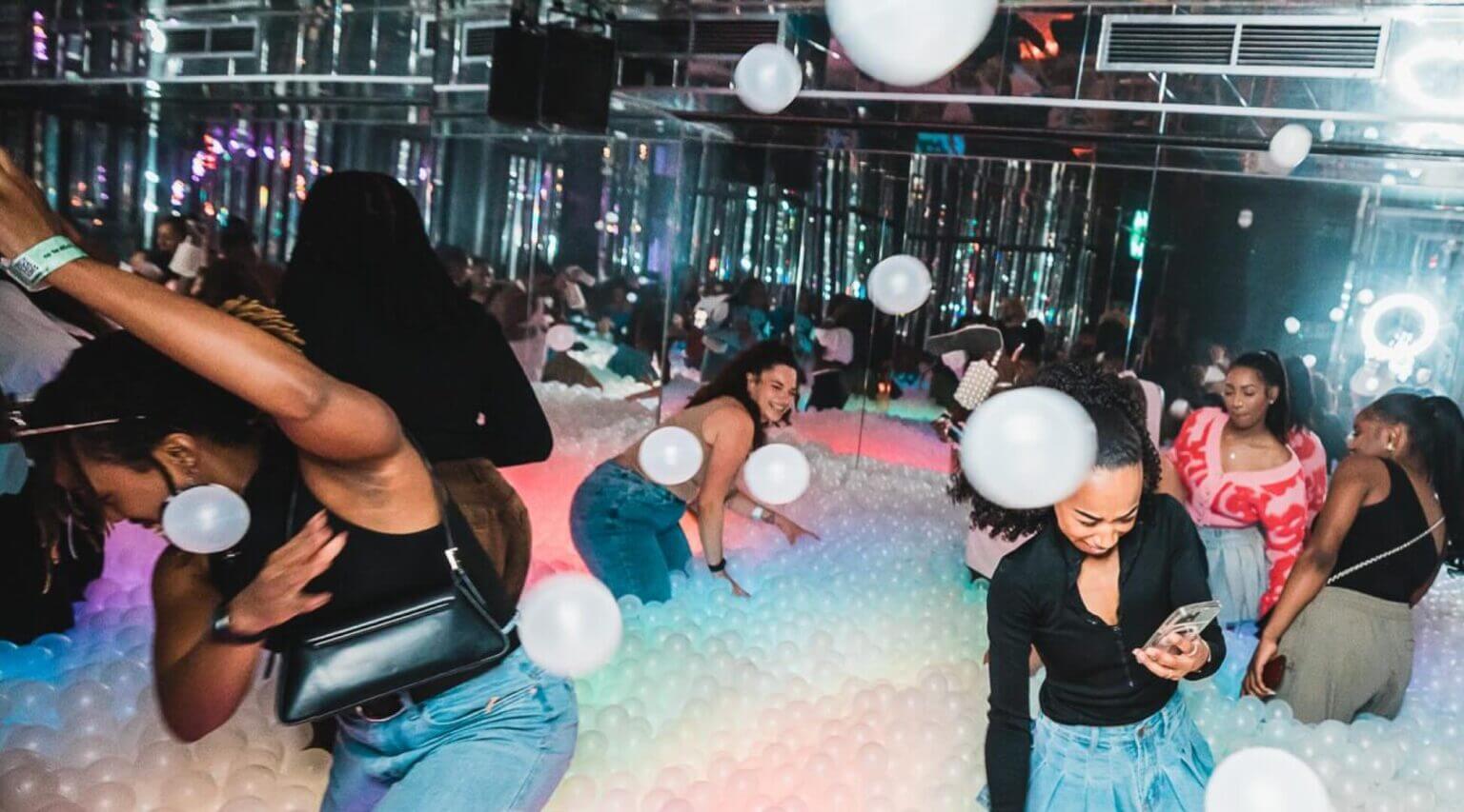 adults playing in a ballpit of white balls