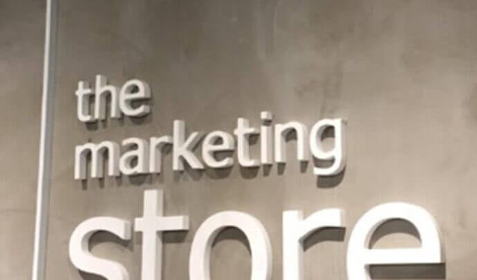 A wall sign reading “the marketing store” in white 3D lettering against a textured grey surface.
