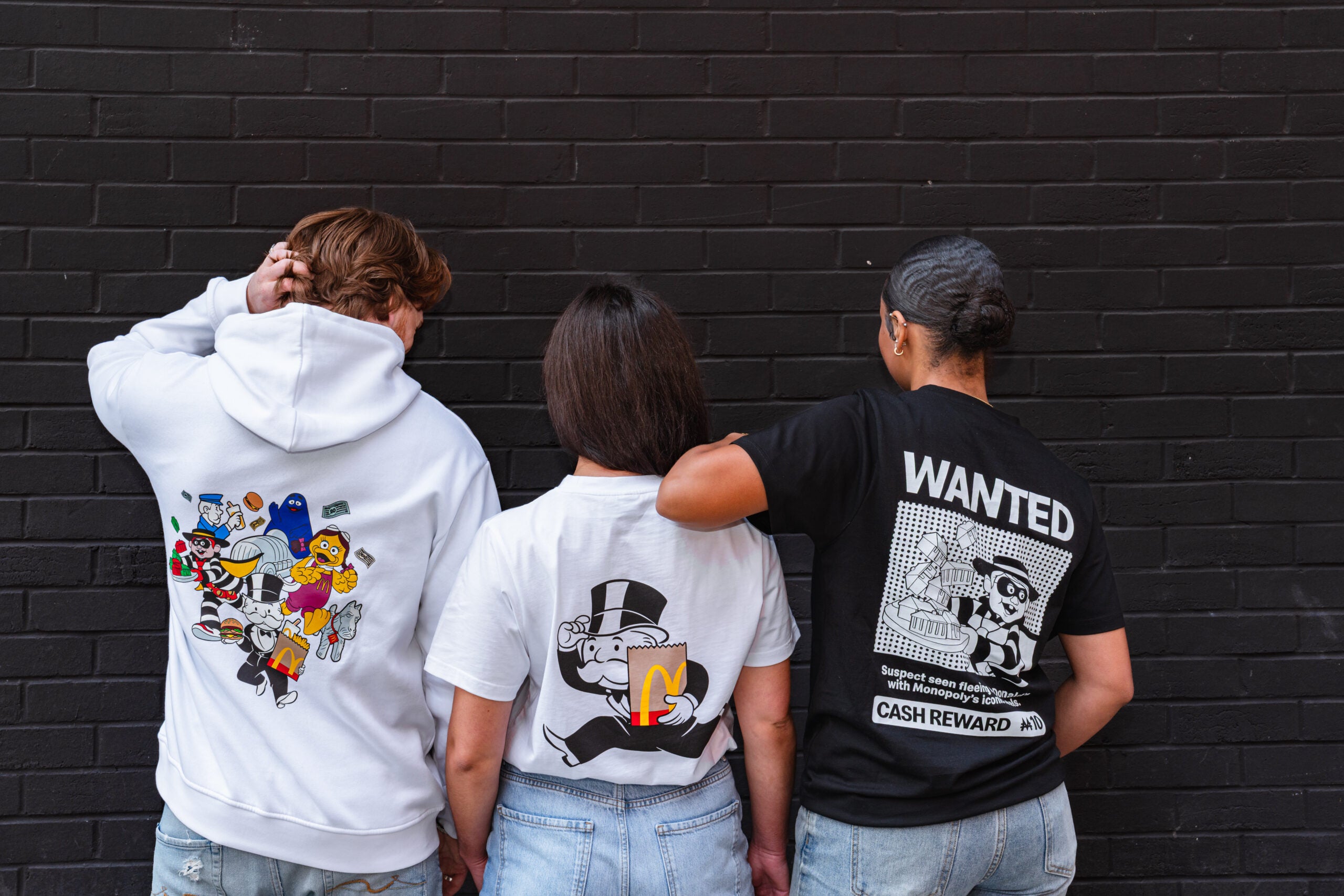 Three people wearing McDonald's monopoly merchandise