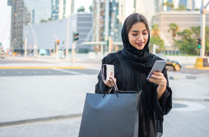 Femme portant un foulard qui tient un sac de courses et un téléphone