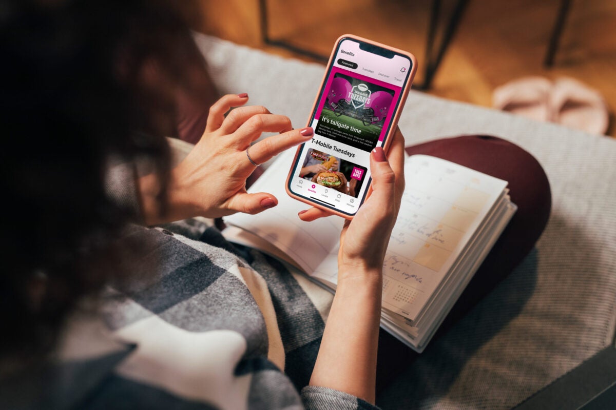 Image of a woman holding a phone with the T-Mobile app