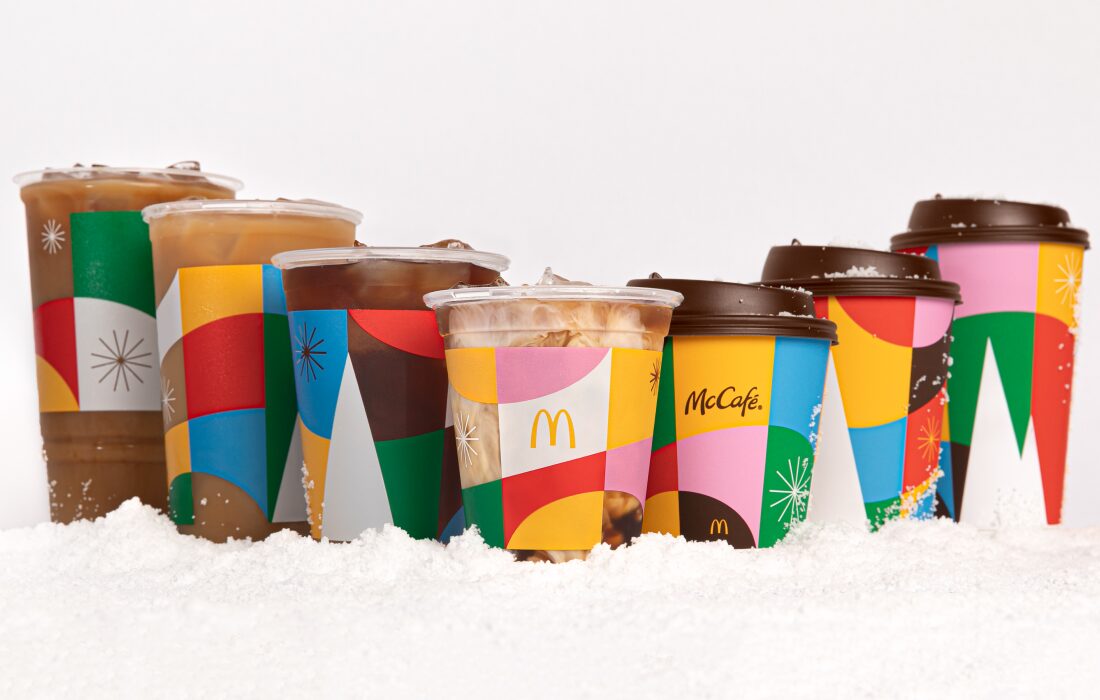 Image of 7 McCafe holiday cups with geometric holiday designs in a row.