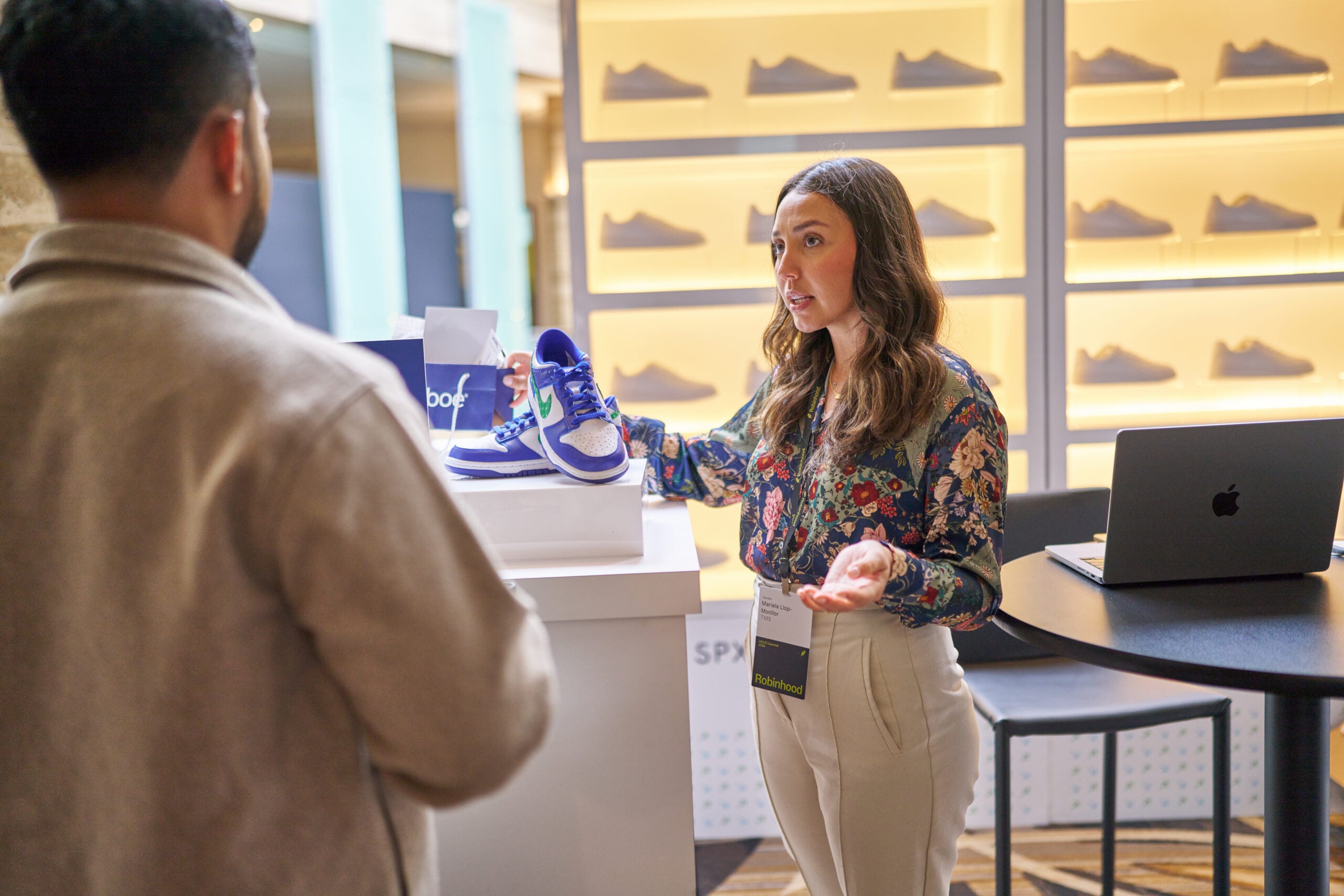 A woman at the Cboe hood Summit activation holding a shoe talking to a man
