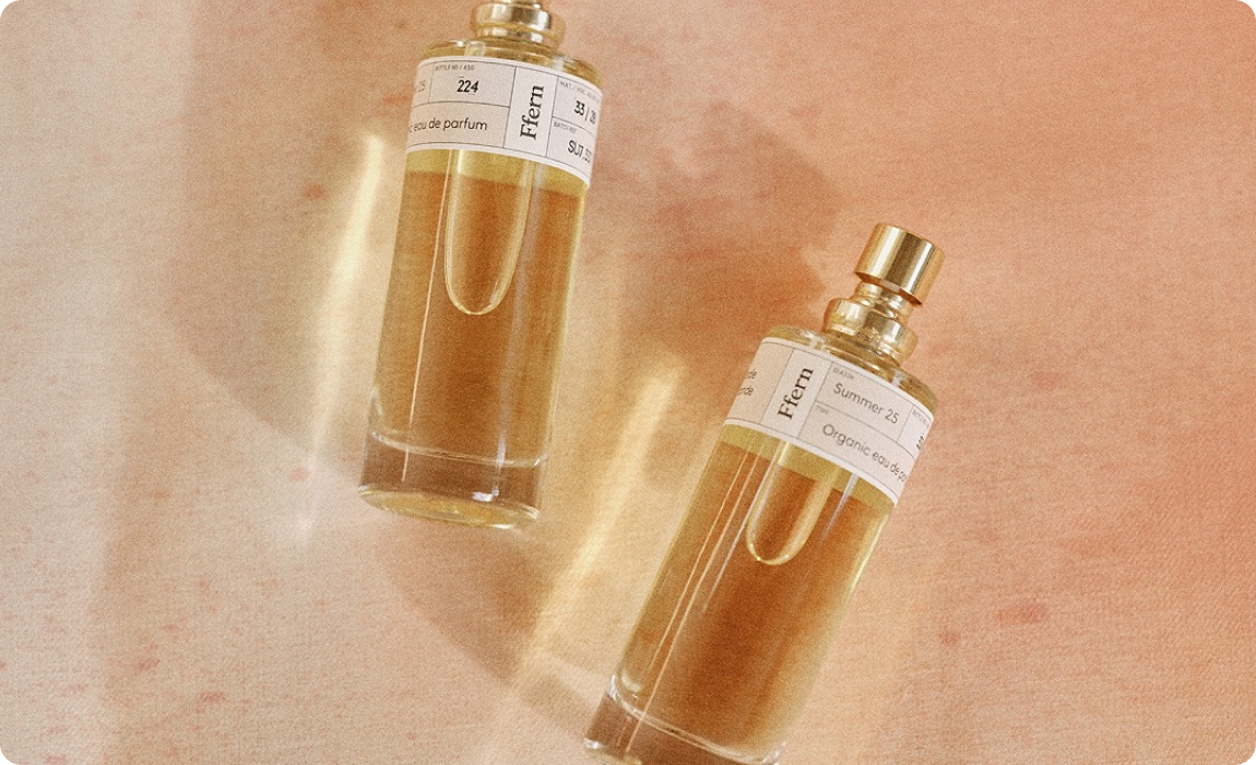 Two glass perfume bottles labelled Ffern on a soft pink surface