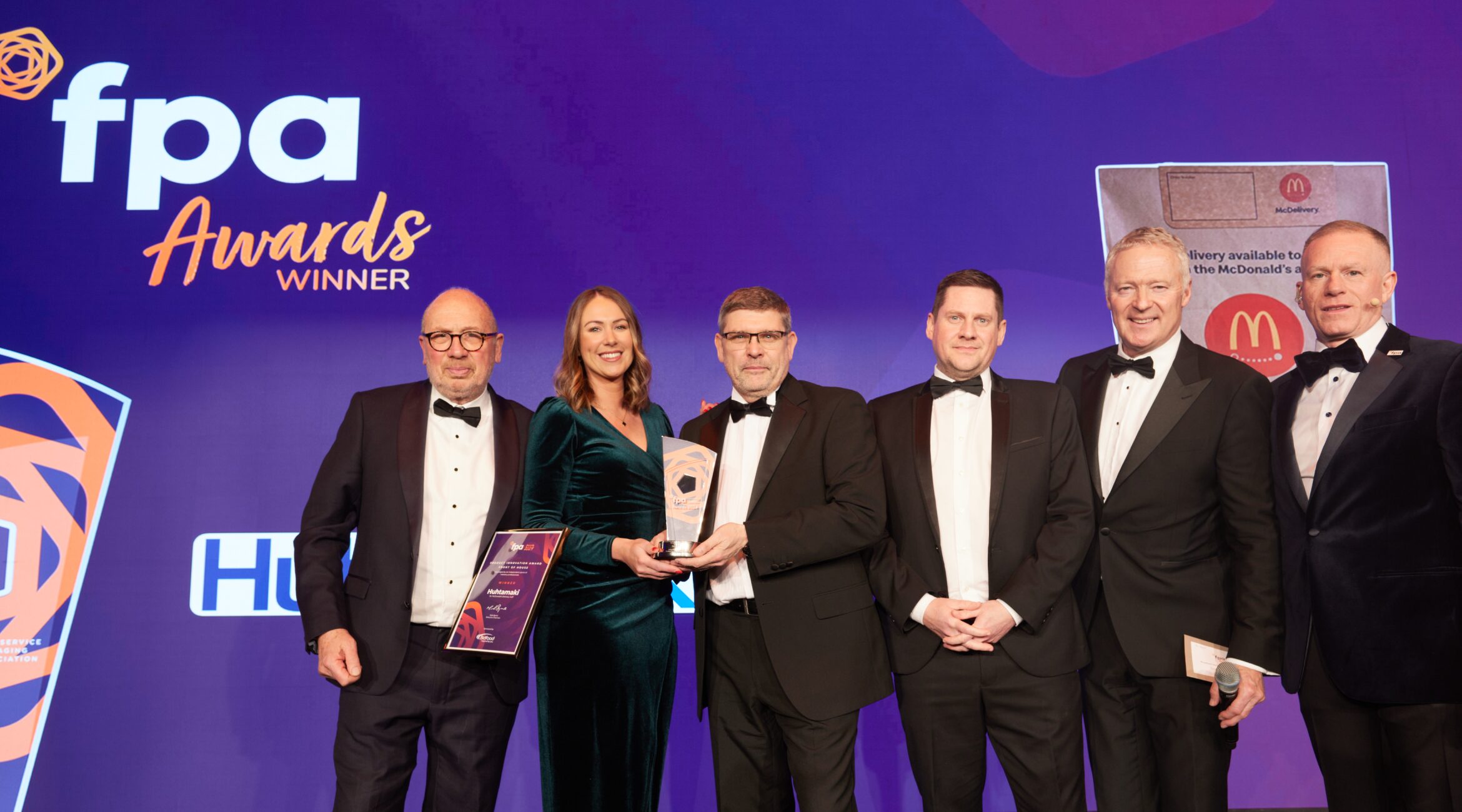 Image of the recipients and presenters of the awards posing in front of the FPA logo at the awards ceremony.