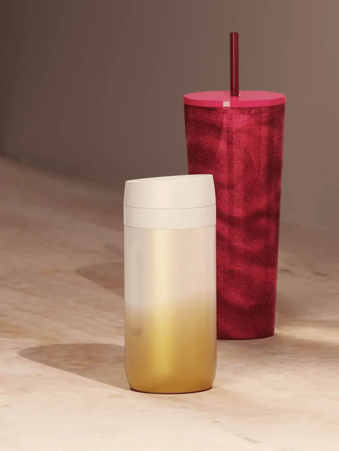 two drinkware products - one red with a red lid and red straw, the other is coloured gold and white gradient with a white lid