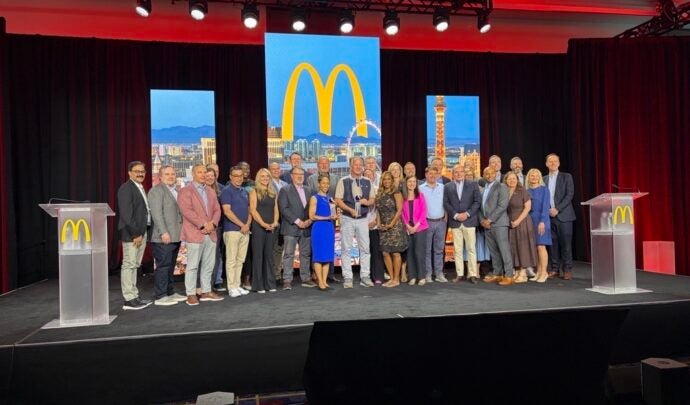 Photo de groupe prise lors de la cérémonie de remise des prix, devant l'écran bleu du McDonald's