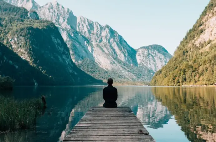 Person sitting on dock looking at mountains