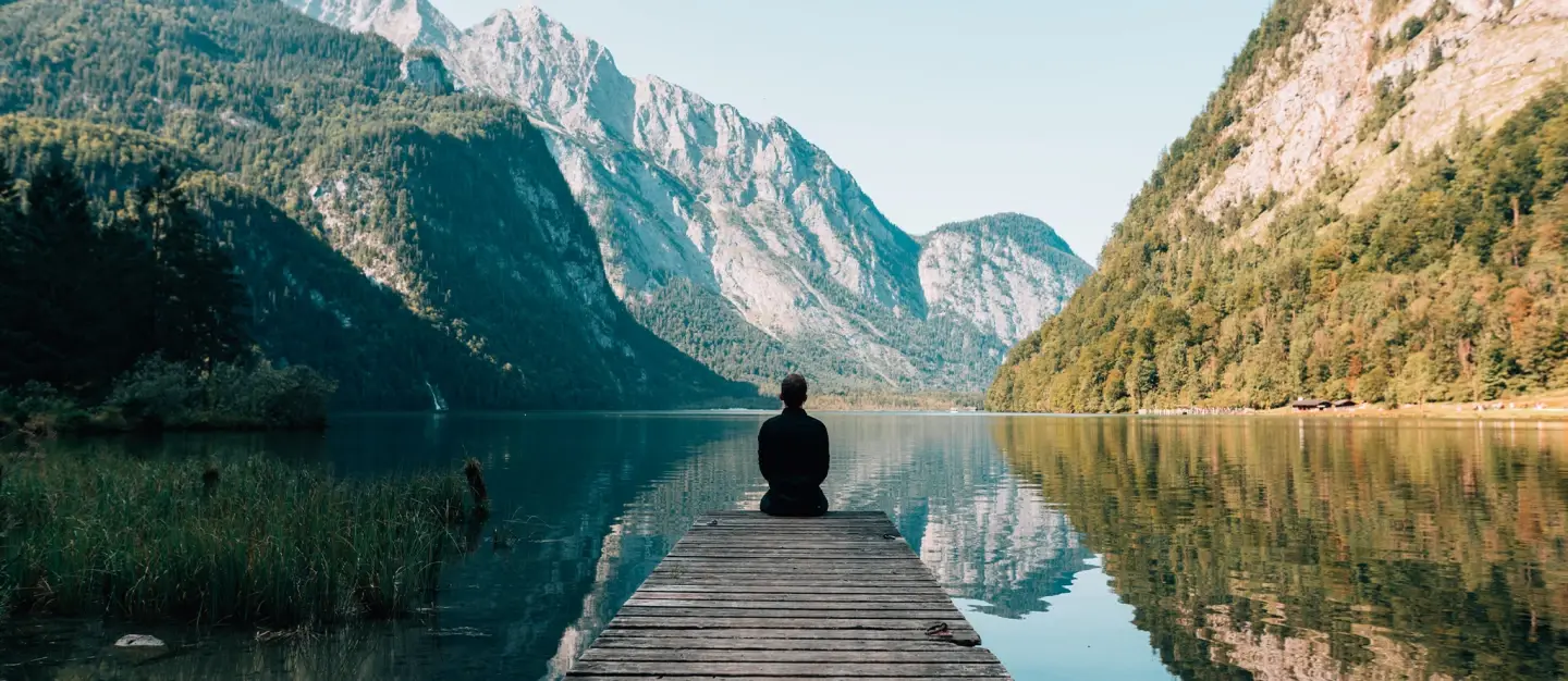 Person sitting on dock looking at mountains