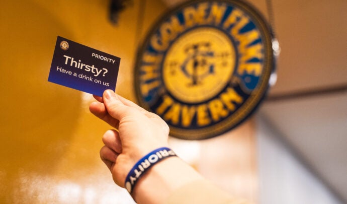 A picture of the Golden Flake Tavern logo with a hand holding a Priority notecard