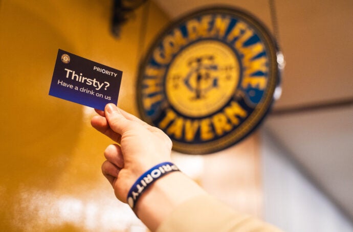 A picture of the Golden Flake Tavern logo with a hand holding a Priority notecard