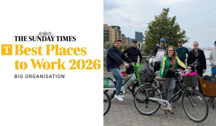 Group of people posing with bikes with the Sunday Times Best Places to Work logo on the left