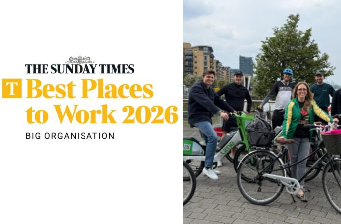 Group of people posing with bikes with the Sunday Times Best Places to Work logo on the left