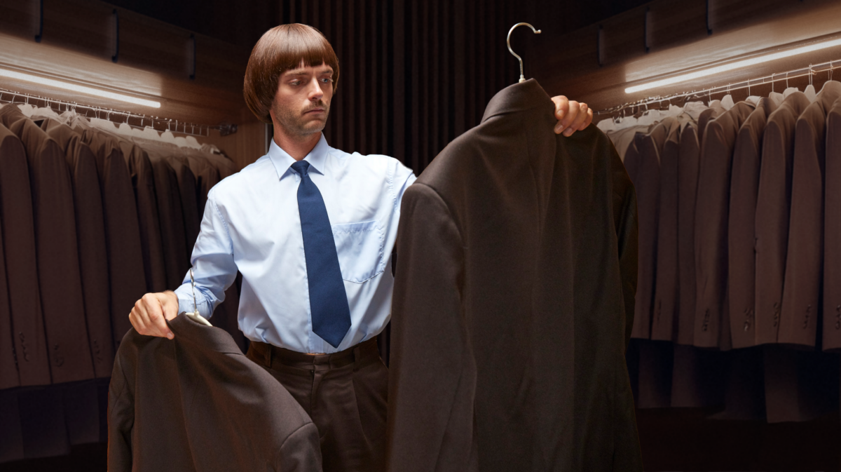 man deciding between suits in closet