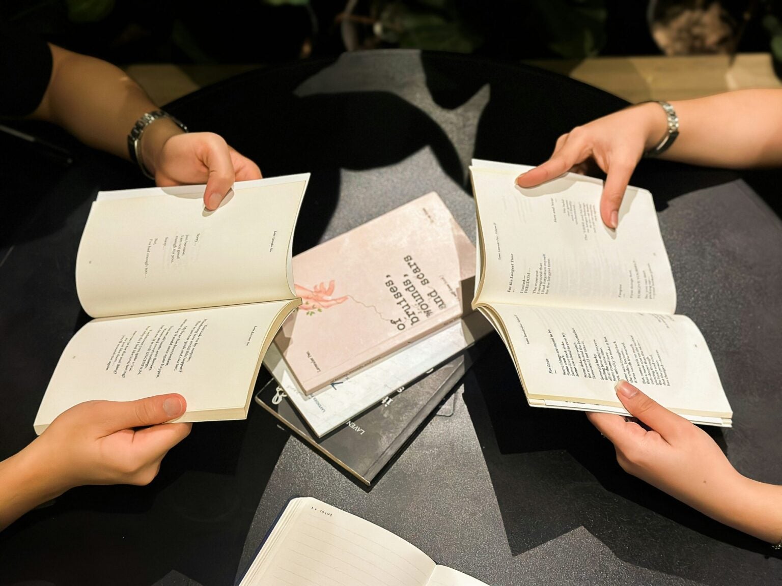 people holding books open around a table