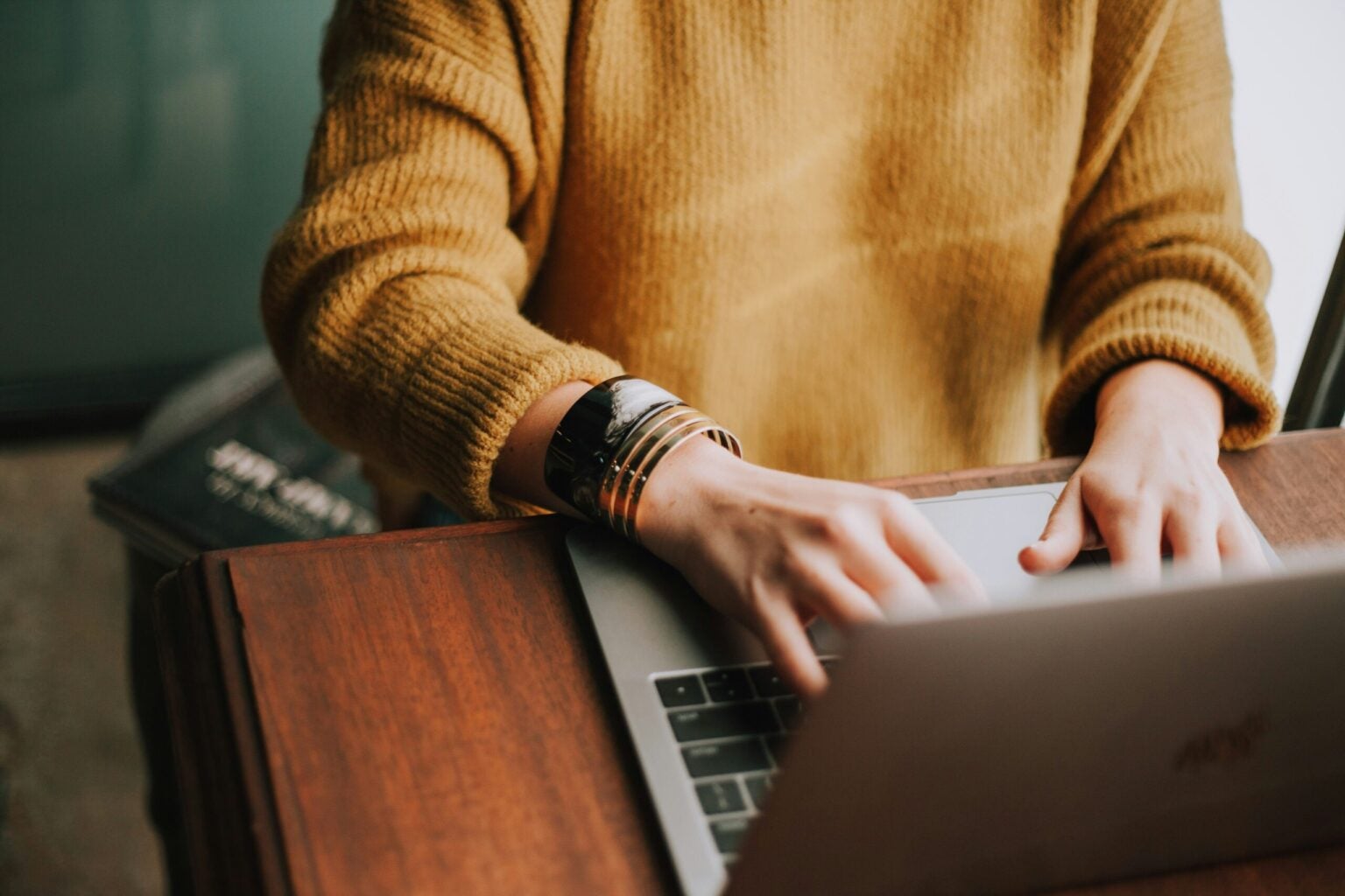 A woman's hands typing on computer with bracelets