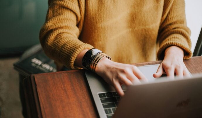 A woman's hands typing on computer with bracelets