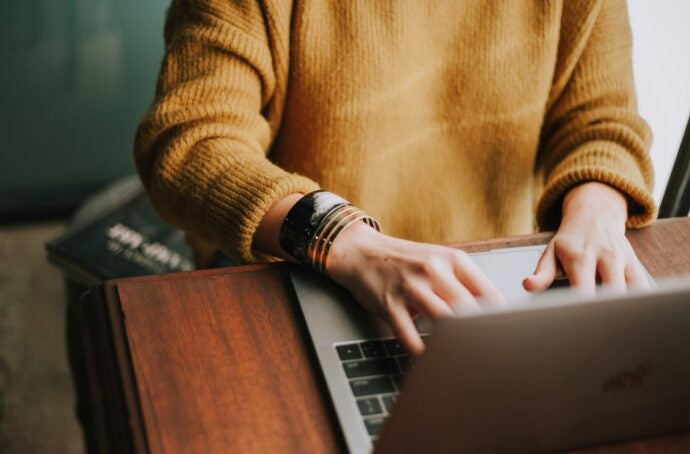 A woman's hands typing on computer with bracelets