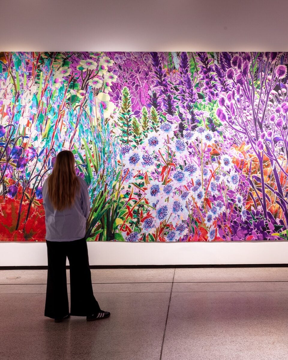 colourful flower painting in an art museum, girl standing staring at painting on the wall