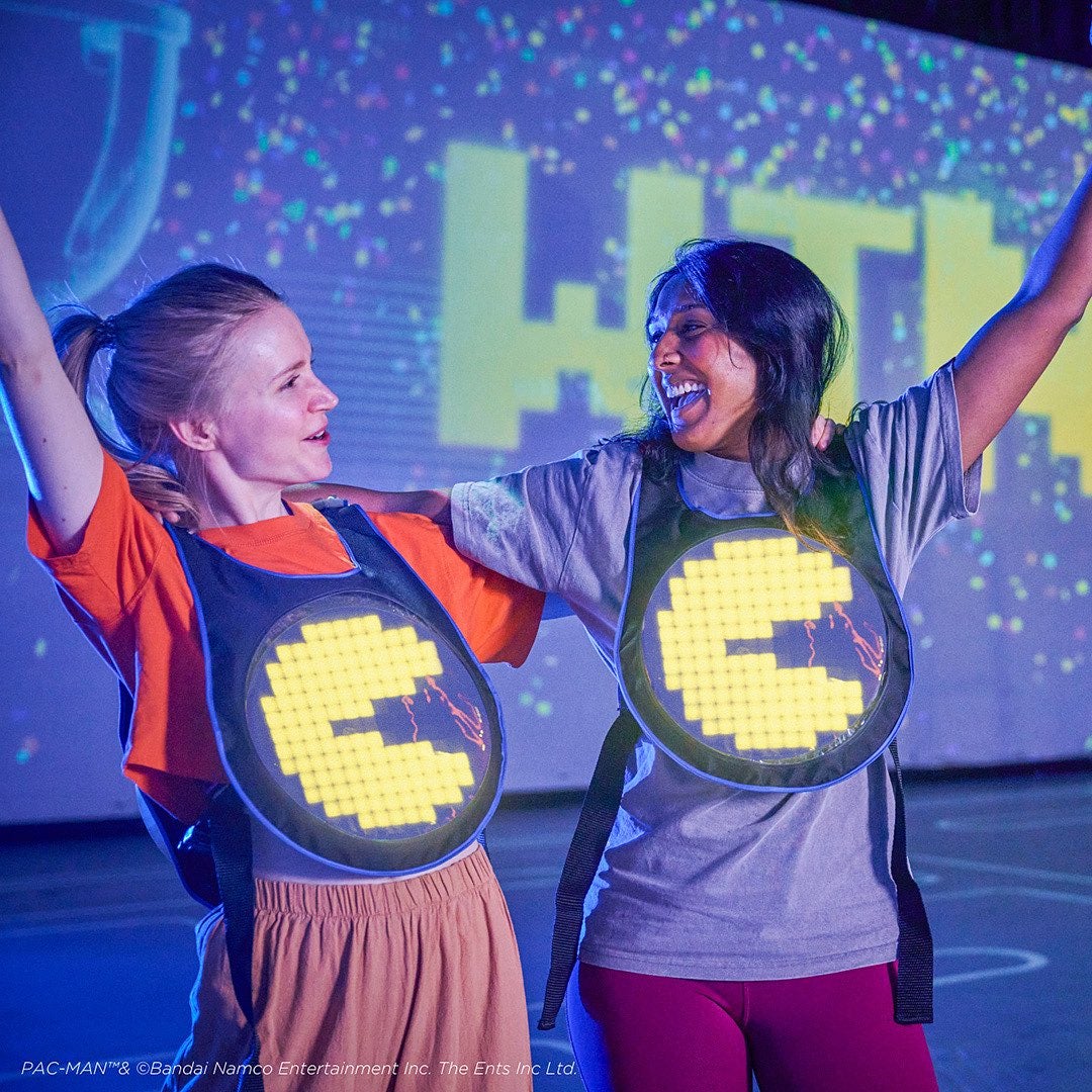 two female friends celebrating while playing an immersive pacman game