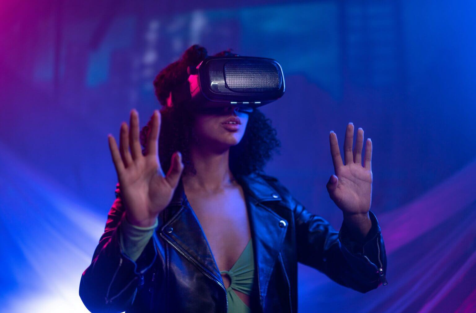 Person using a VR headset with hands raised in a neon lit room
