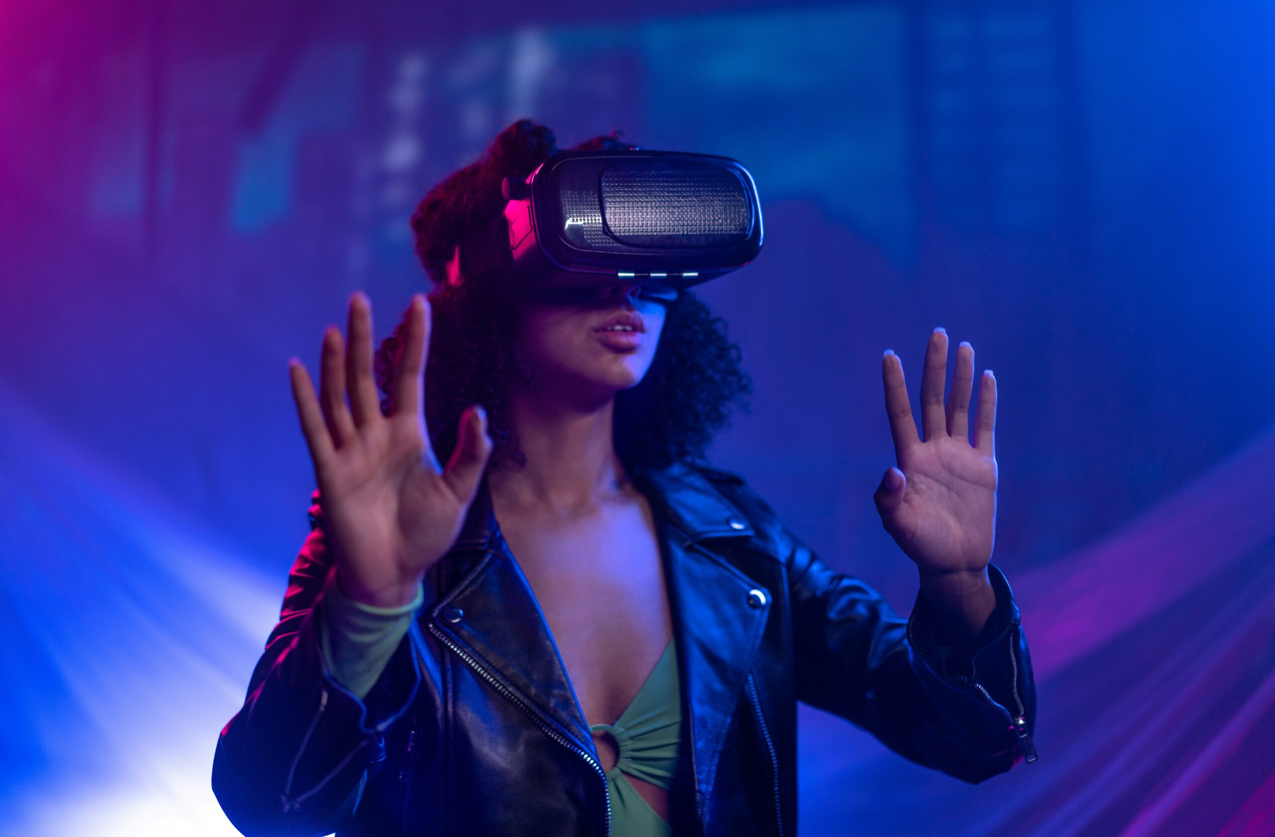 Person using a VR headset with hands raised in a neon lit room