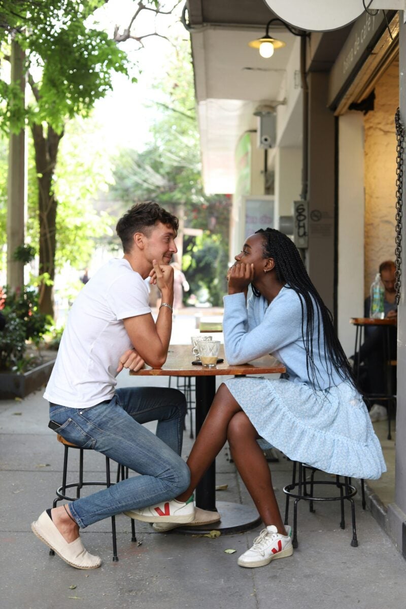 a couple sitting opposite each other outside in a coffee shop