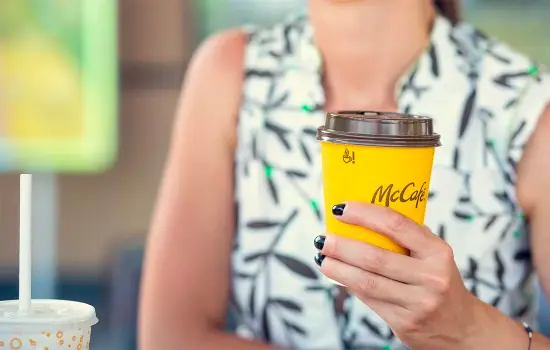 Une personne blanche tient un gobelet en fibre de McDonald's