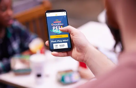 Personne tenant son téléphone ouvert pour le jeu Double Peel in-app