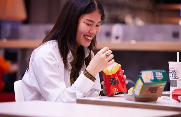 Woman eating fries and enjoying Double Peel meal at McDonald's