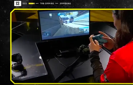 Gamer plays on Samsung mobile device in front of computer screen