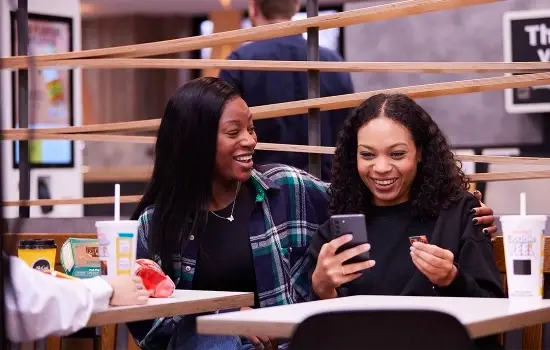 Two women looking at the McDonald's Double Peel Monopoly game on their phone