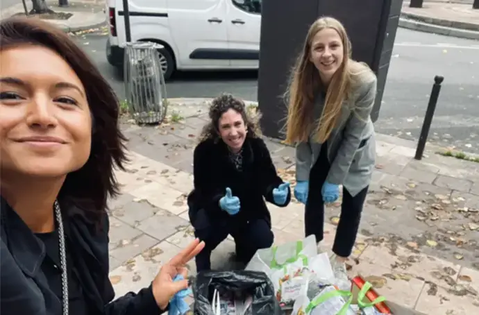 three women cleaning up trash from the sidewalk