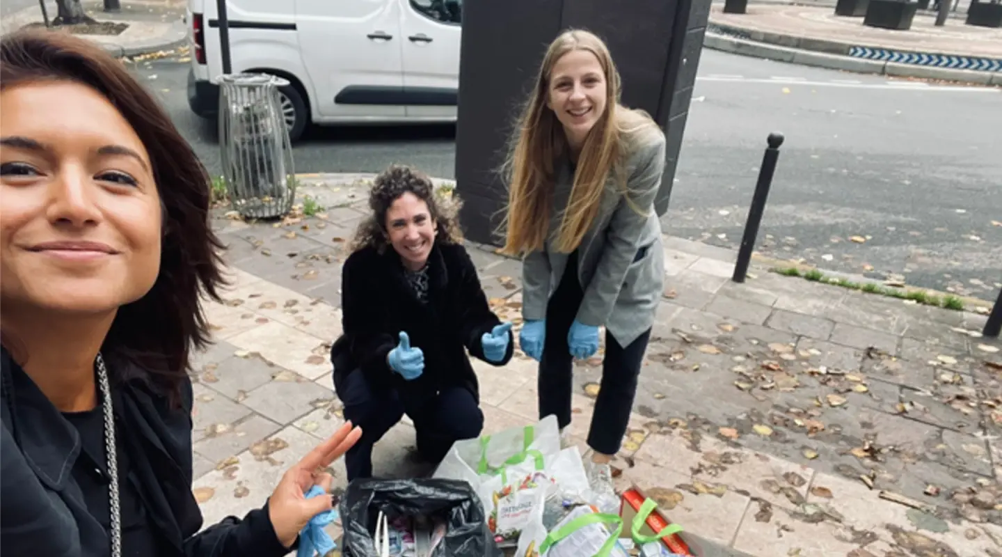 three women cleaning up trash from the sidewalk