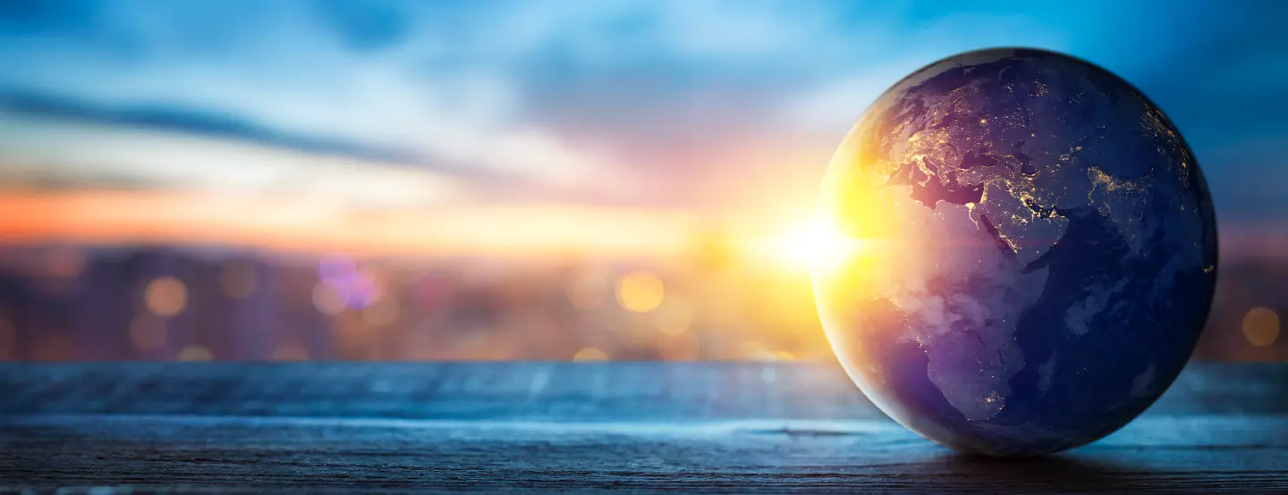 Globe on wood surface with sunset behind