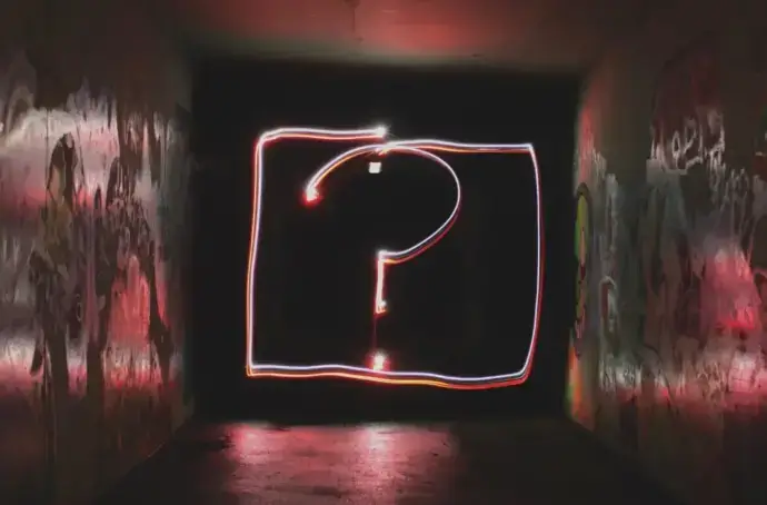 Dark room with graffiti walls and question mark made of lights