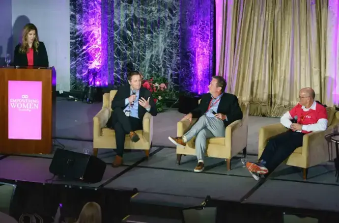 John Hartline seated in the middle of the stage at the women empowerment conference