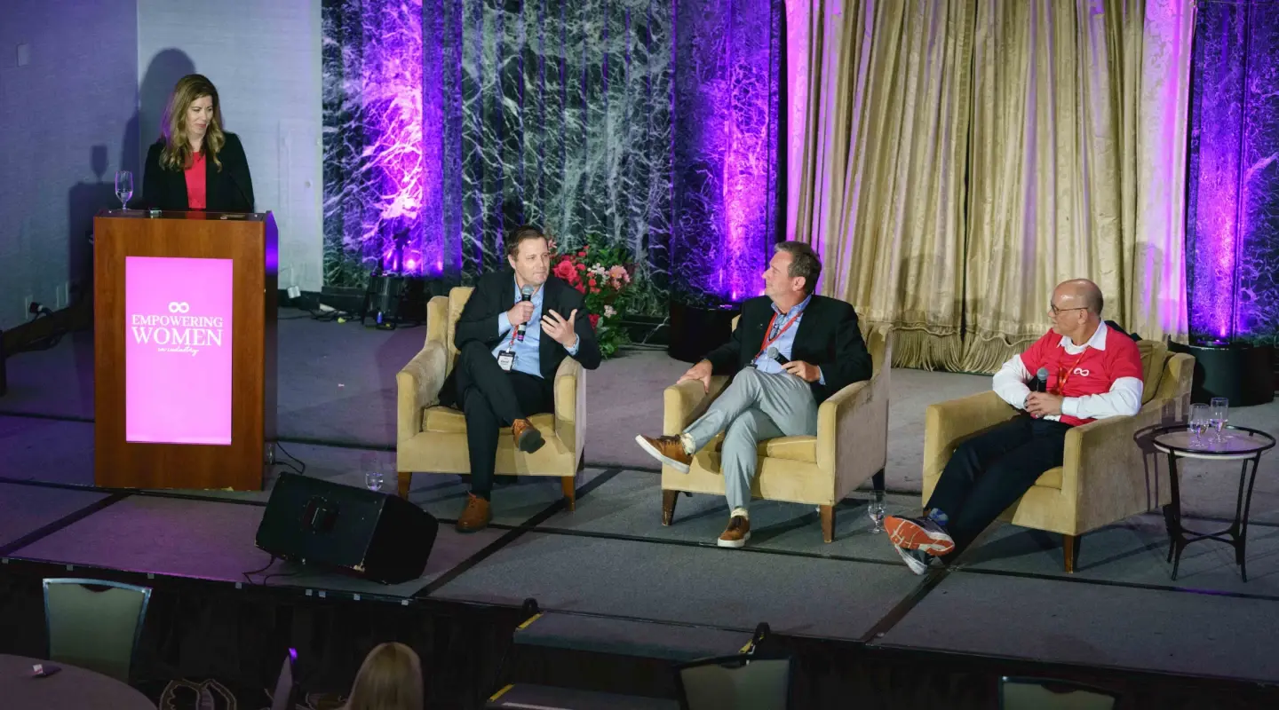 John Hartline seated in the middle of the stage at the women empowerment conference
