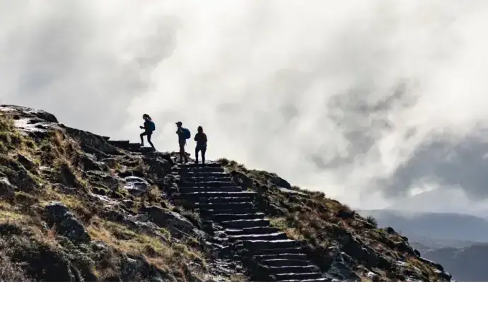 One person leading two others up a mountain
