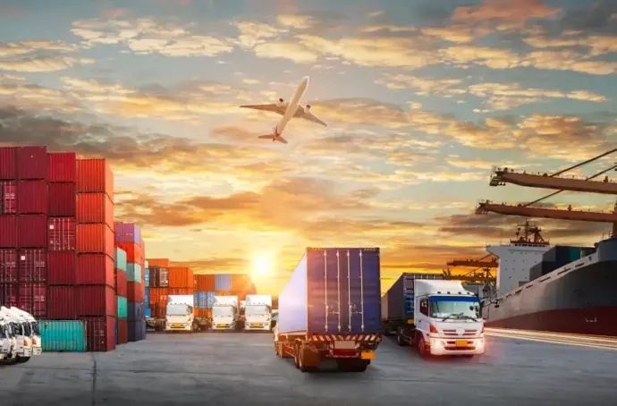 Wide view of shipping dock with lots of containers and trucks, one plane, one boat