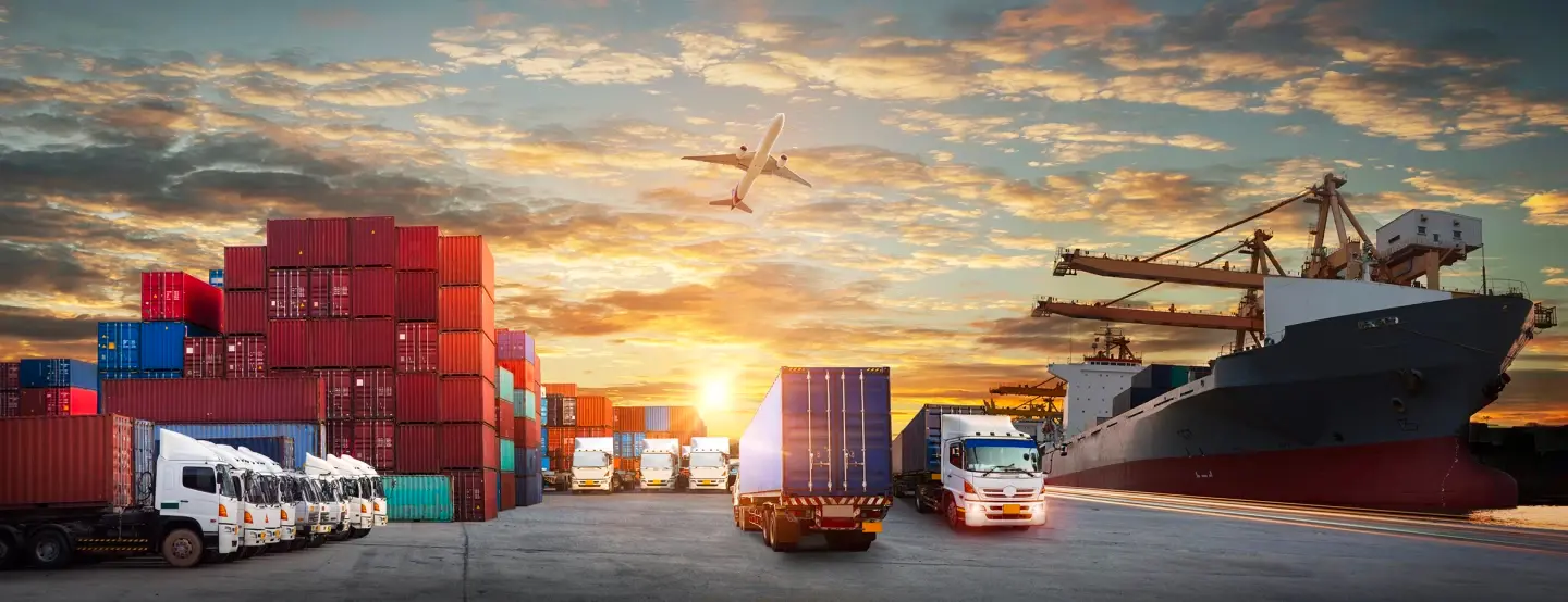 Wide view of shipping dock with lots of containers and trucks, one plane, one boat