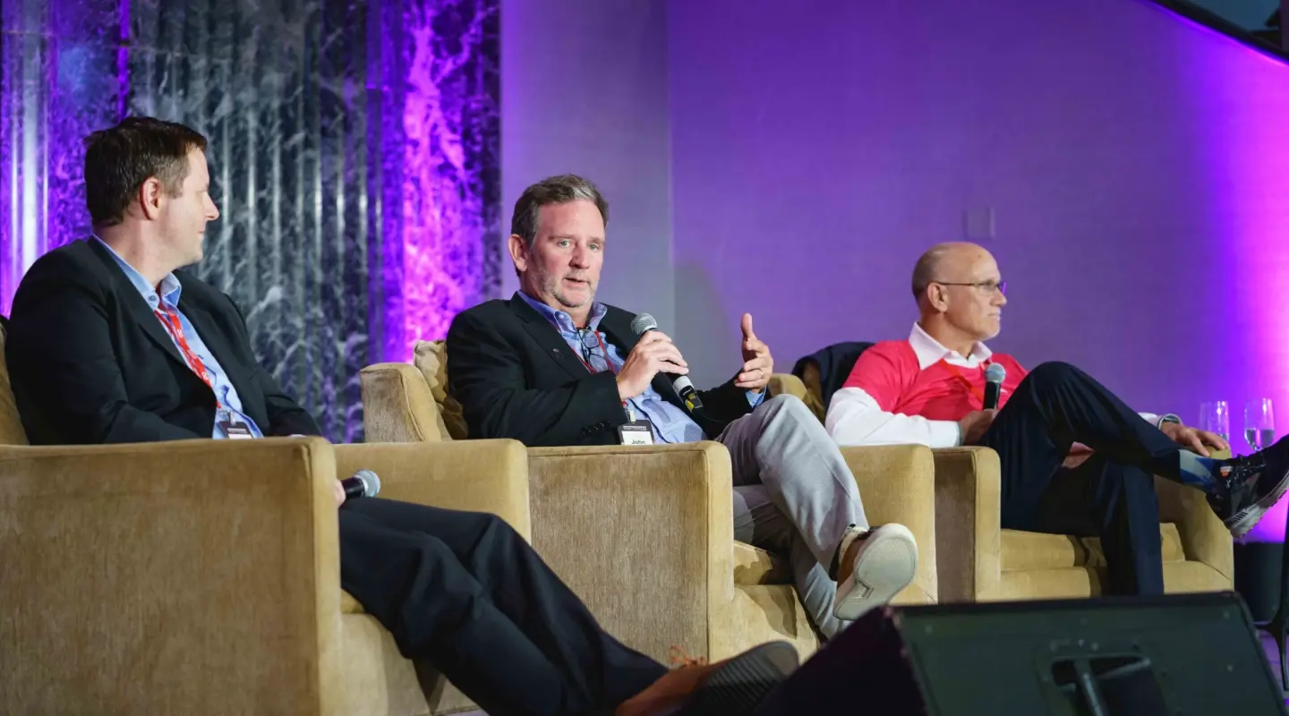 John Hartline in the middle speaking at the women empowerment conference with one person on either side of him
