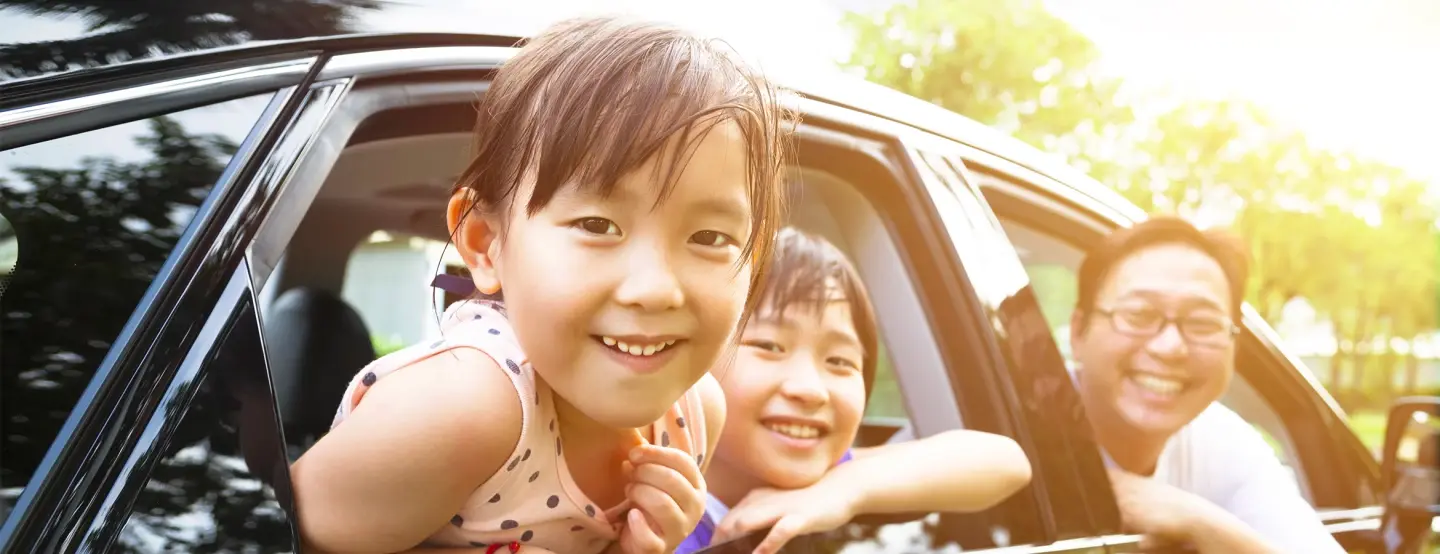 Man and two children smiling, leaning out the windows of black car