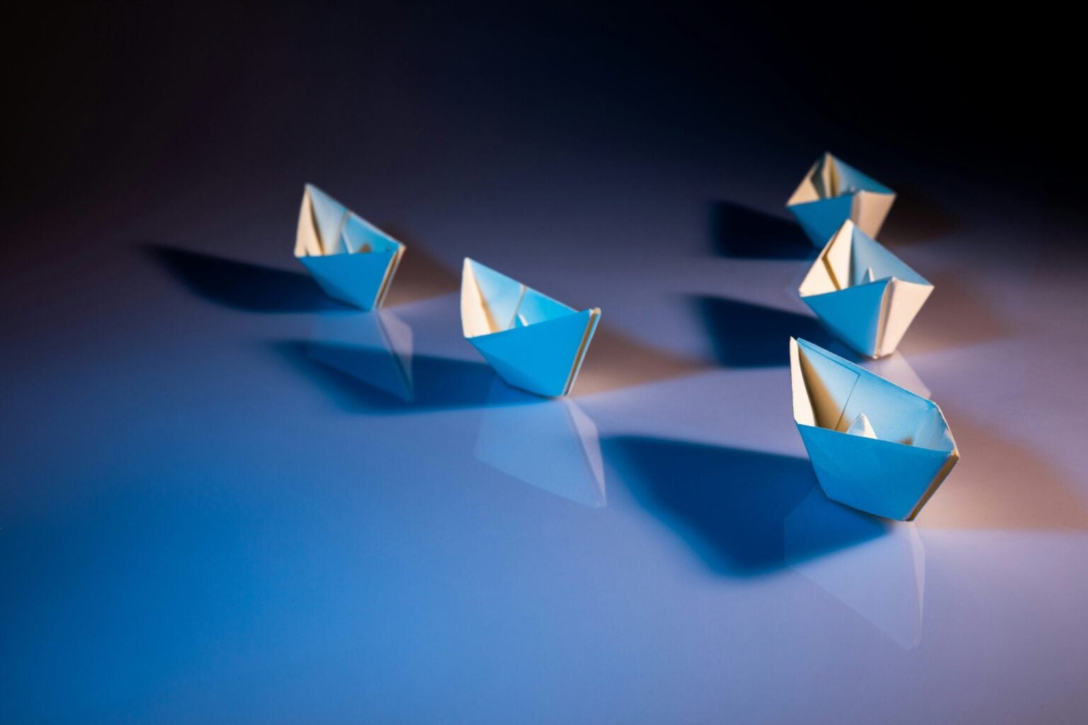 Five paper boats following in sequence